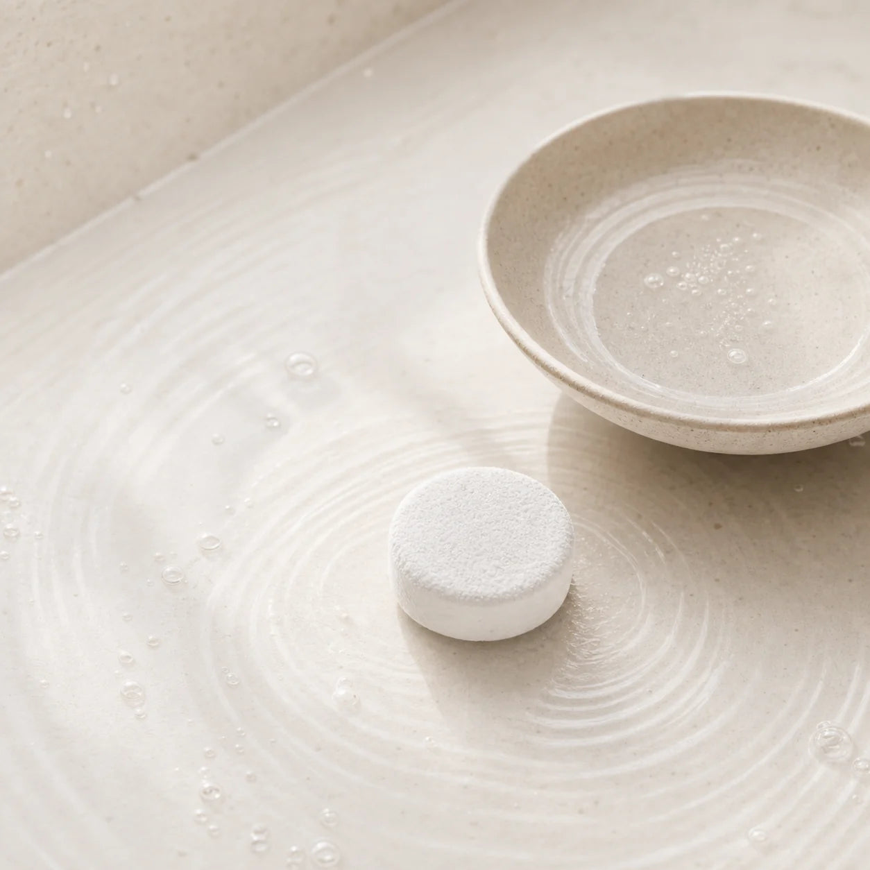 A carbonated tablet beside soft water ripple marks